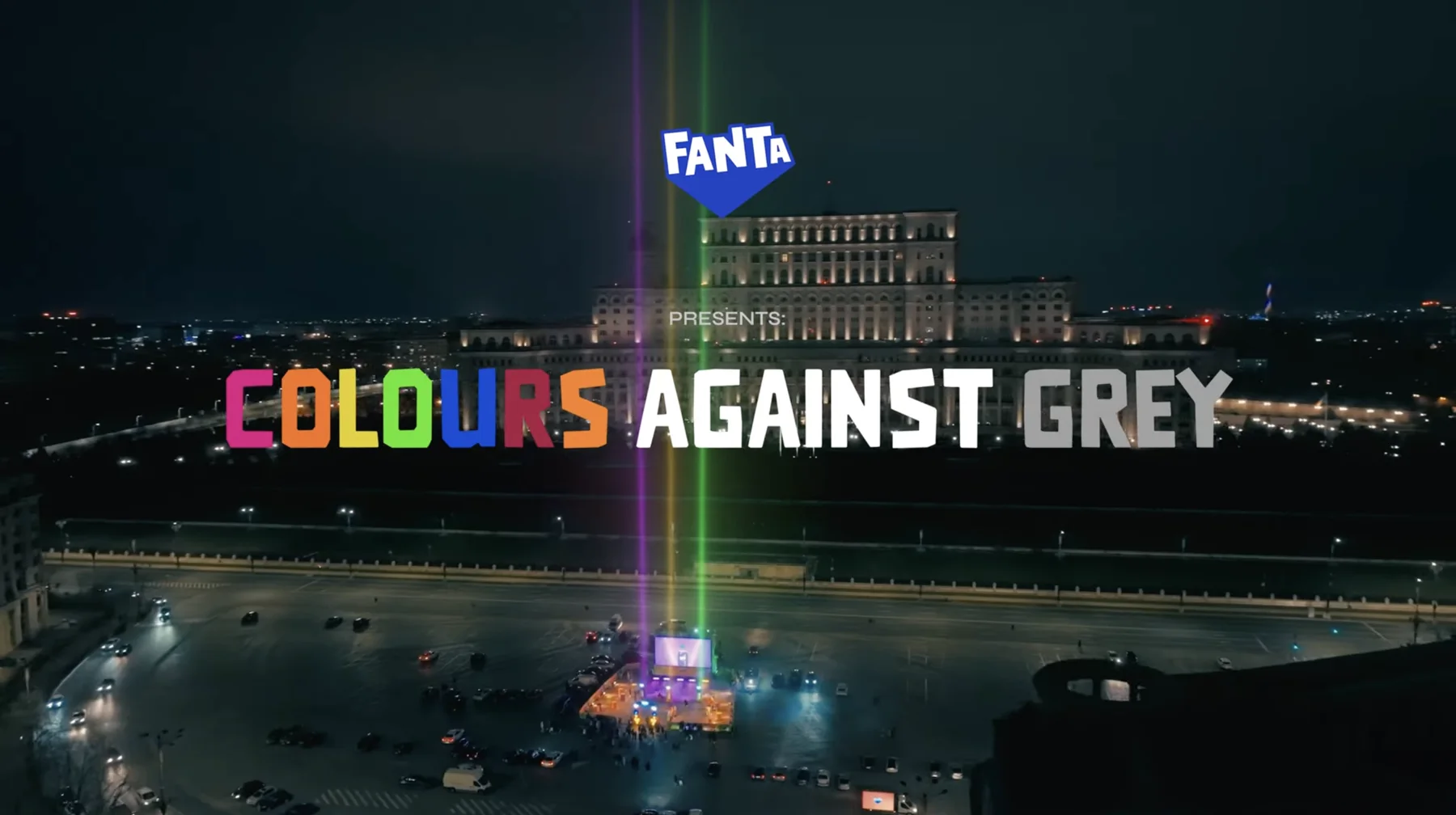 Aerial night view of the Palace of Parliament in Bucharest with colour beams and the title Fanta presents Colours Against Grey.