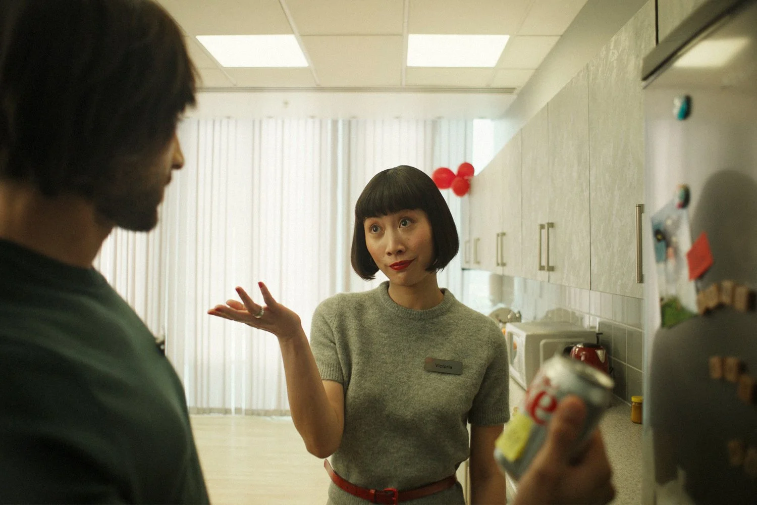 Film still: two colleagues in an office kitchen, one holding a personalised Diet Coke can.