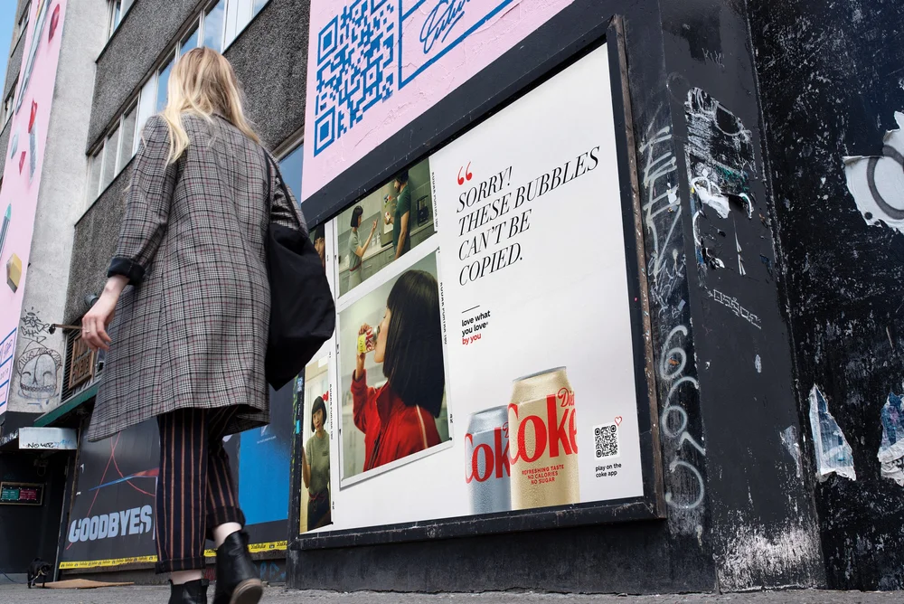 Fly-posted Diet Coke poster on a graffitied wall in Berlin reading Sorry! These bubbles can't be copied.